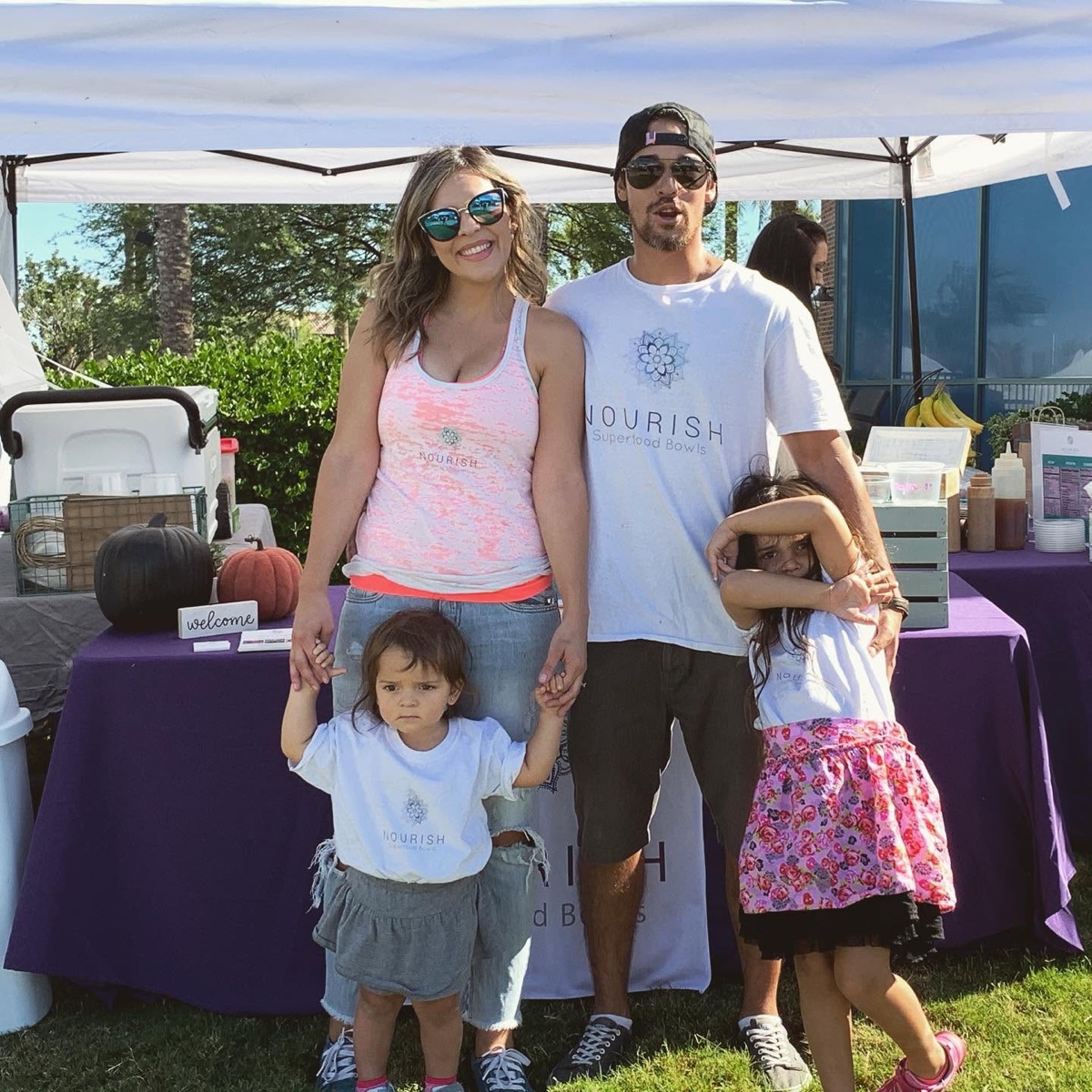 Reyna and family working a Nourish pop-up booth under a white canopy